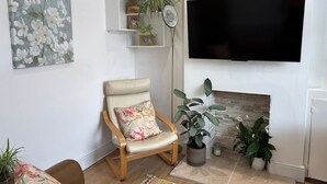 Ein Wohnzimmer mit Holzstuhl, einem Gemälde, einem Flachbildfernseher und einem Kamin.