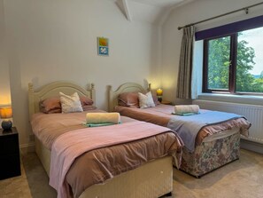 Une chambre double avec deux lits, chacun doté d’une table de chevet, d’une lampe et d’une fenêtre avec des rideaux.