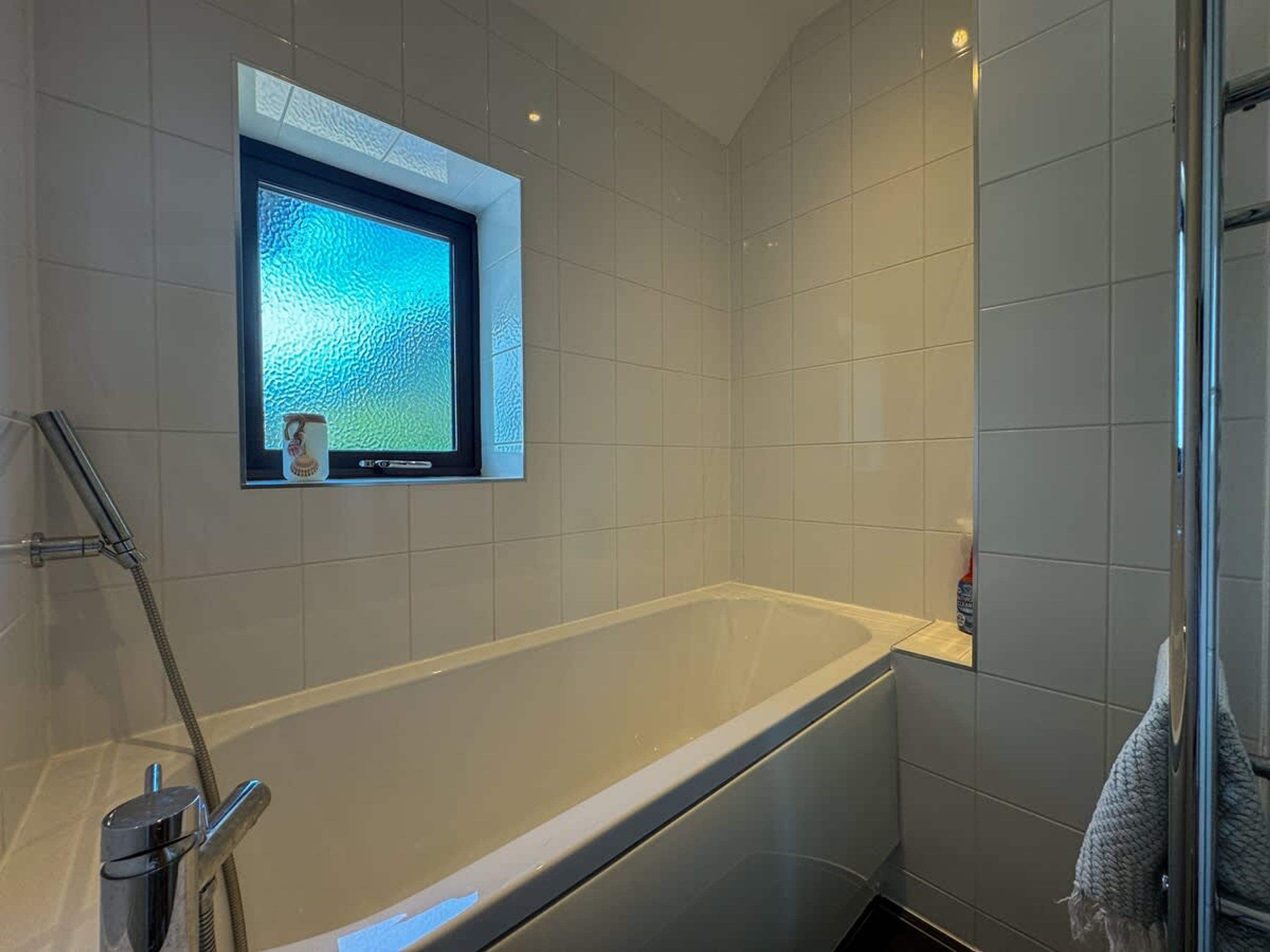 Une salle de bain moderne avec une baignoire, une douche et une fenêtre donnant sur un beau paysage.