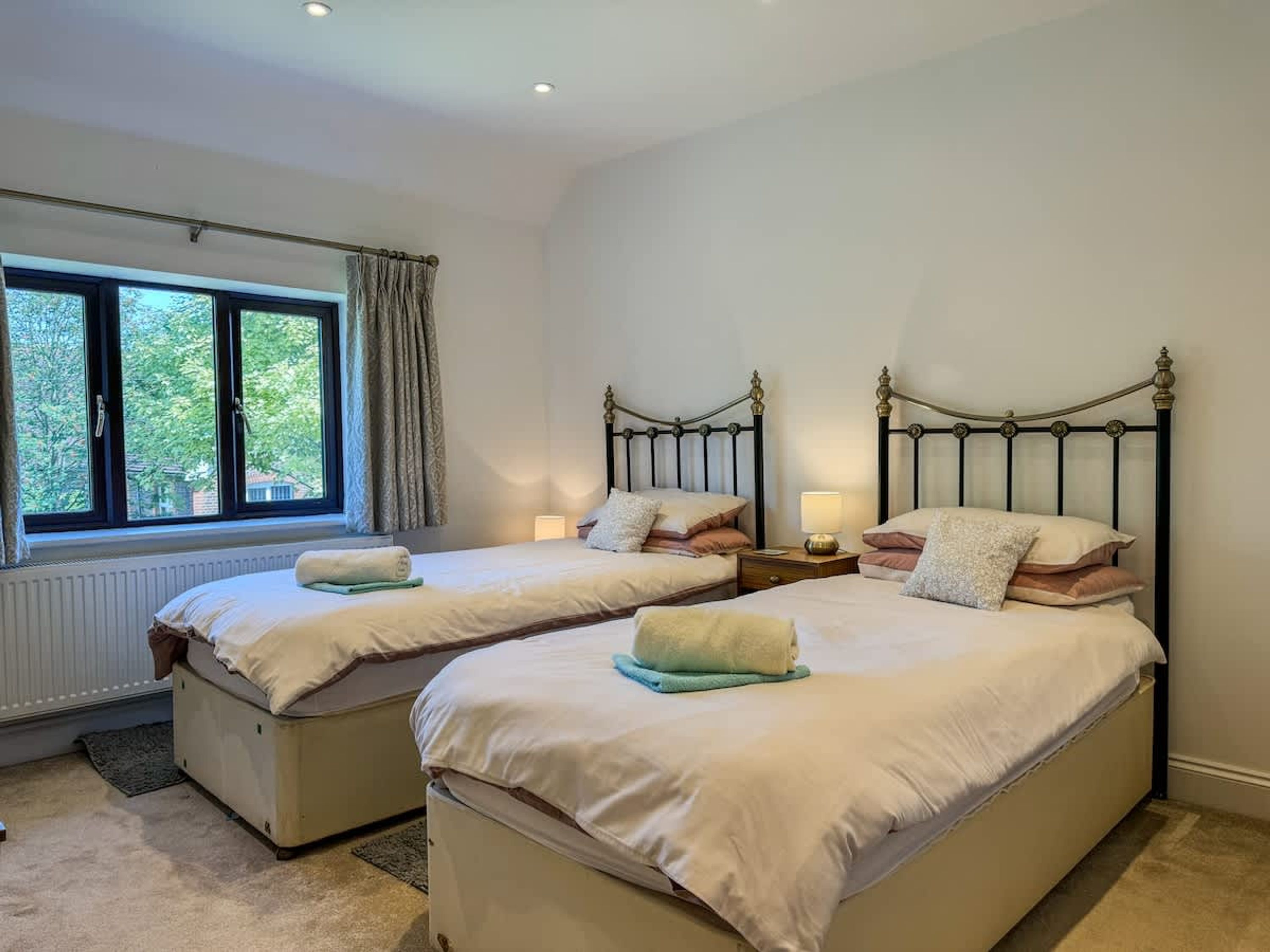 Quarto duplo com duas camas, janela com cortinas e radiador.