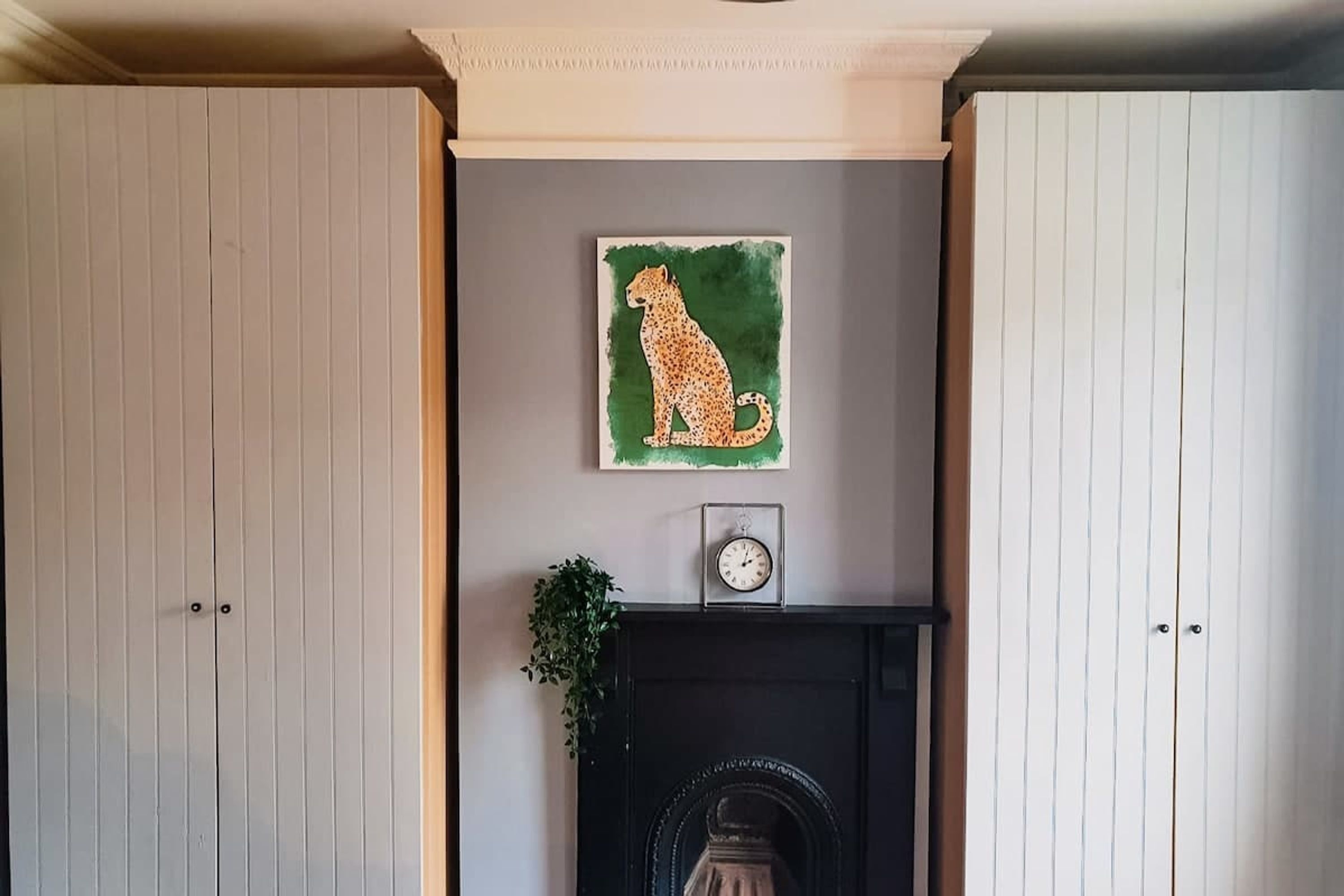 Une pièce avec une cheminée, une horloge et un tableau encadré au mur.