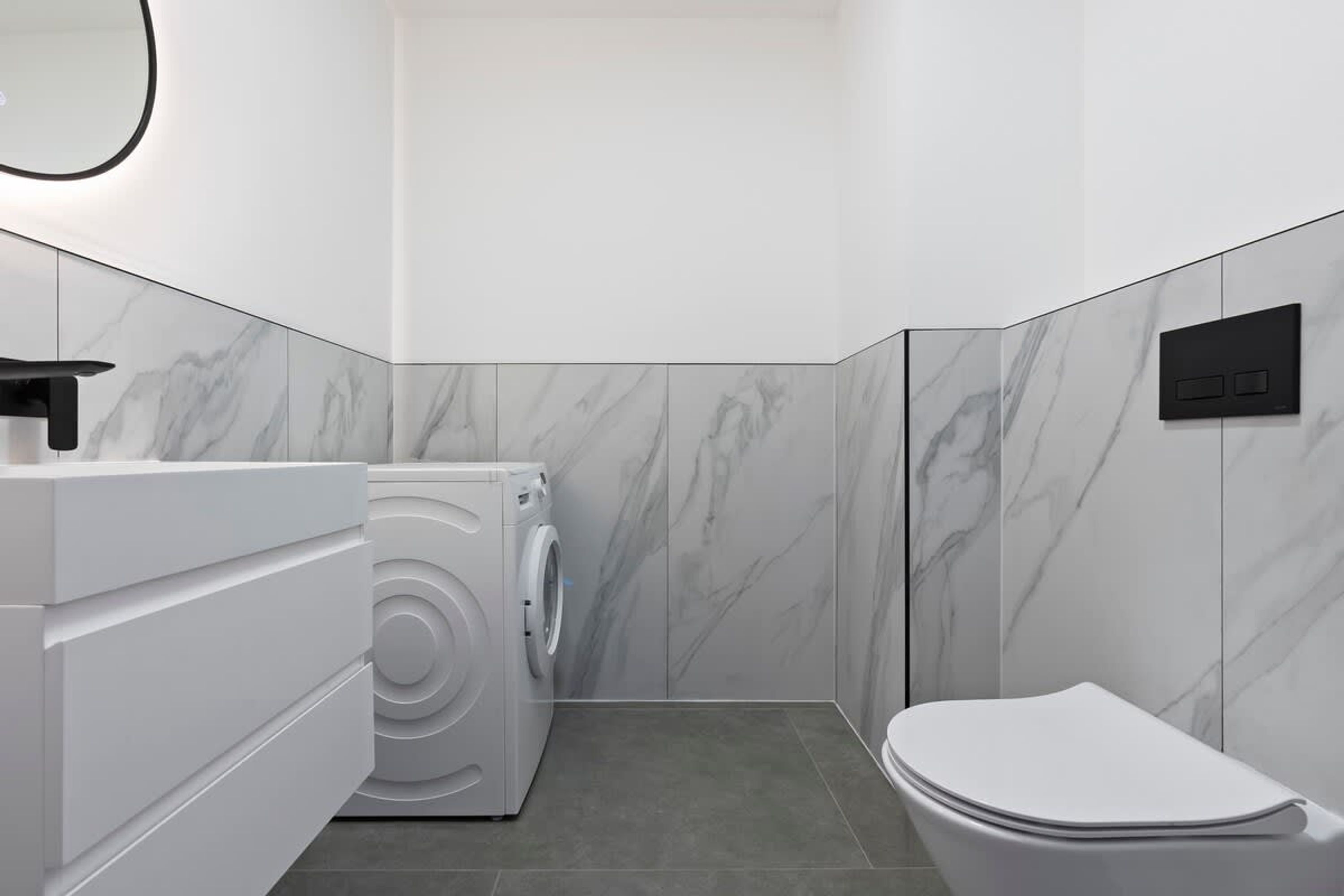 Un baño pequeño con lavadora, inodoro y un tocador moderno.