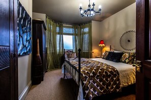 Quarto com cama, uma cadeira, abajur, janela e lustre.