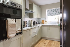 A modern kitchen with a built-in oven, a microwave, and a digital clock displaying 15:50.