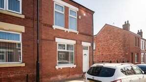 A residential building with a brick facade, white-framed windows, and a parked car. - Perfect Booking Stylish 3 Bed Family Home (Doncaster)