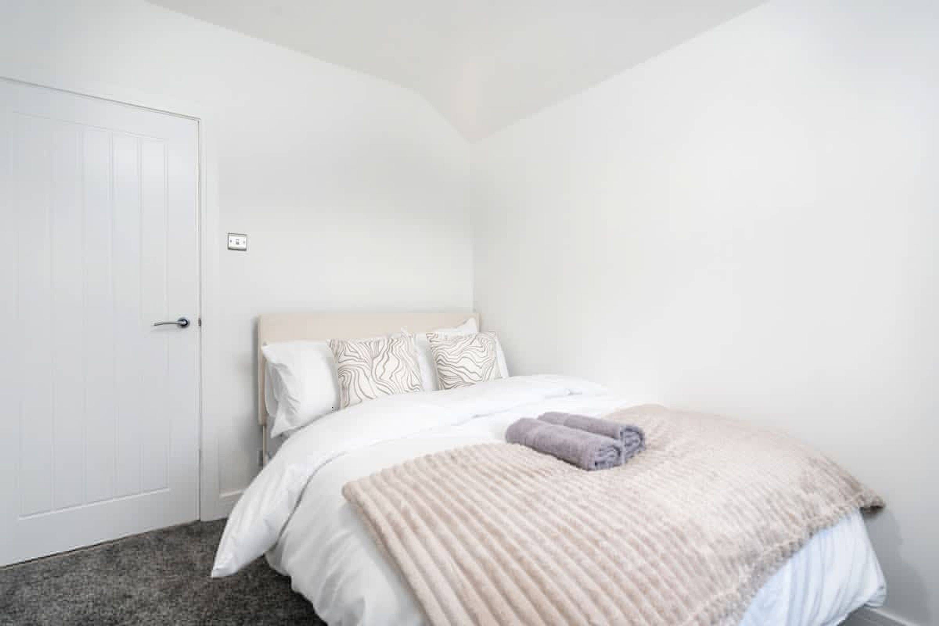 A bedroom with a bed, a door, and a wall socket.