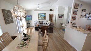 A modern living space with a dining area, a kitchen island, and a seating area. - Villa Willow Wood 3-bedroom Home Private Pool (Inverness)