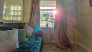 Una habitación con sofá, ventana con cortinas y vistas al exterior.