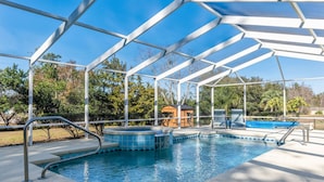 Piscina coberta com hidromassagem, rodeada por estrutura metálica e árvores.