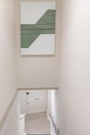 Eine Treppe mit modernem Design, eine weiße Tür unten und ein Wandbild darüber.
