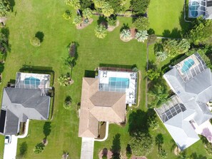 An aerial view of a residential area with three houses, each with a swimming pool and a large garden. - Villa Anita Spacious Villa With Private Pool (Inverness)