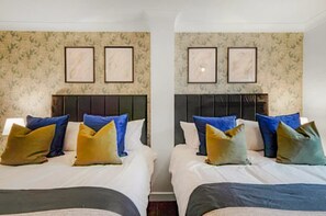 A hotel room with two beds, each with a headboard, and a wall with framed pictures. - Perfect Booking 3 Bed Home in Whitechapel (London)