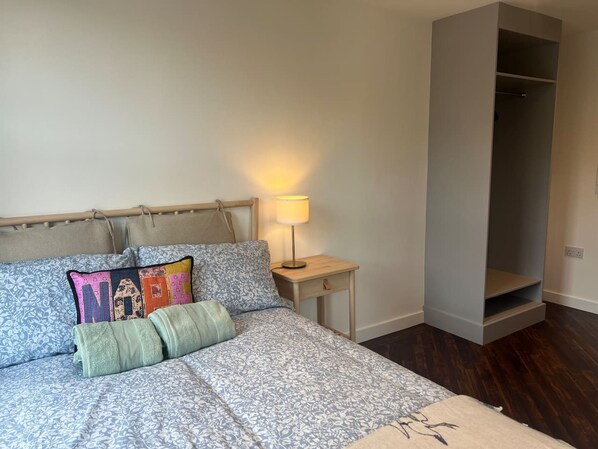 A bedroom with a bed, a bedside table with a lamp, and a wardrobe. - Private Ensuite Room With Patio (London)