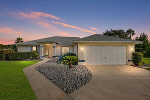 Ein zweistöckiges Haus mit Garage, Auffahrt und einem angelegten Vorgarten.