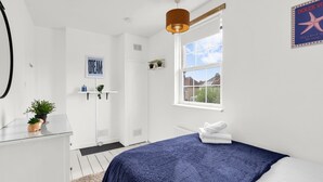 Ein Schlafzimmer mit einem Bett, einem Fenster, einer Tür, einem Regal mit Pflanzen und einem Schild an der Wand.
