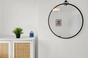 A white wall with a round mirror, a potted plant, and a framed picture. - Modern 2BR House Near DLR | Isle of Dogs (London)