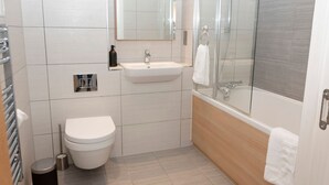 Un baño moderno con inodoro, lavamanos y ducha.
