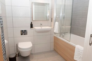 A modern bathroom with a toilet, sink, and shower. - Garden Flat in Central Battersea (London)
