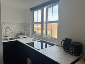 Eine Küche mit Spüle, Herd, Toaster und einem Fenster mit Blick auf Gebäude.