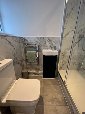 A compact bathroom with a toilet, sink, and shower. - Ensuite Double Room Near Clapham (London)