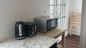 A compact kitchen with a marble countertop, a kettle, a toaster, and a microwave. - Ensuite Double Room Near Clapham (London)