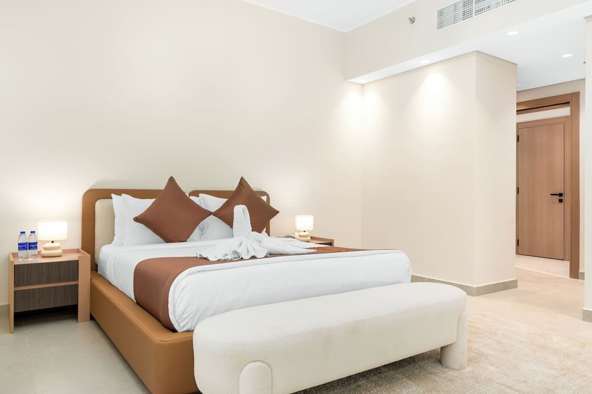 Une chambre d’hôtel moderne avec un grand lit, des tables de chevet et une porte.