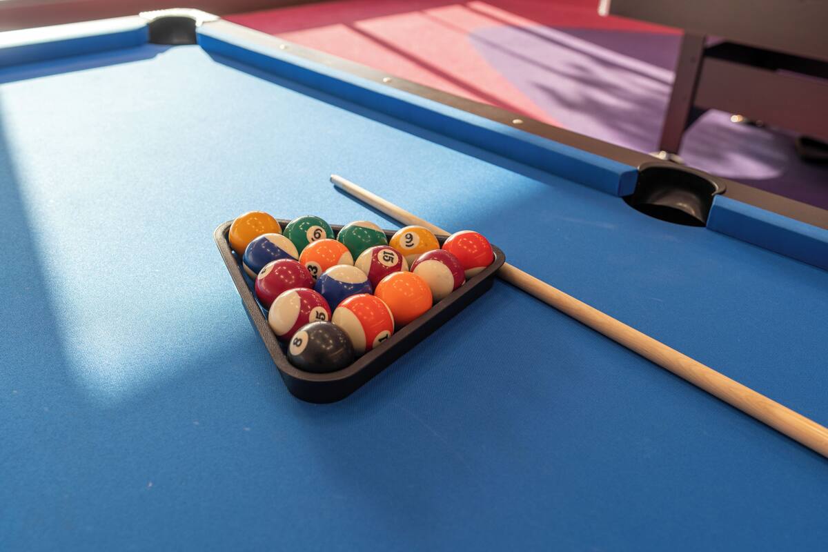 Une table de billard avec un jeu de billes et une queue de billard.