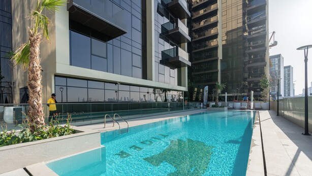 Un edificio moderno con piscina, ventanas amplias y una palmera.