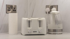 Eine Küchenarbeitsfläche mit einem GE-Toaster, einem Papiertuchhalter, einem Glas Wasserkocher und einer Steckdose.