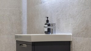Ein Badezimmer mit einem modernen Waschbecken, einem Spiegel und einer Toilette.