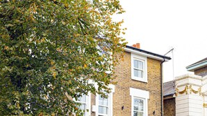 A residential building with a brick facade, white window frames, and a black door. - Modern Brixton Flat 3 (Magherafelt)