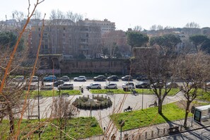 Ein Parkplatz mit Autos, einer kreisrunden Grünfläche und Gebäuden im Hintergrund.