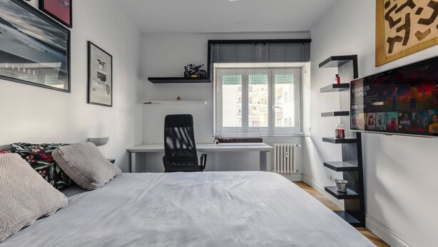 Un dormitorio con cama, escritorio, silla y radiador.
