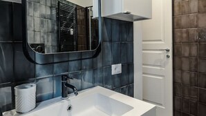 Un baño moderno con un lavamanos blanco, un espejo y un armario.