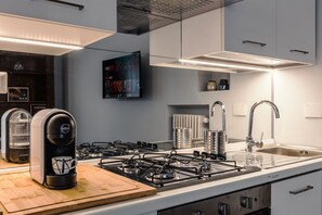Eine moderne Küche mit Gaskochfeld, Kaffeemaschine und einem großen Fenster.