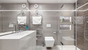 A modern bathroom with a glass-enclosed shower, a large white sink, and two towel racks. - Charming Mews House in Kensington (London)