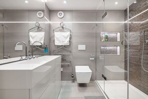 A modern bathroom with a glass-enclosed shower, a large white sink, and two towel racks. - Charming Mews House in Kensington (London)