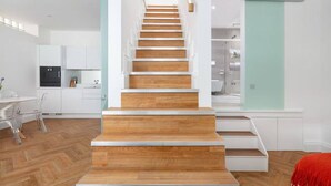 A modern interior with a wooden staircase leading to a second floor. - Charming Mews House in Kensington (London)