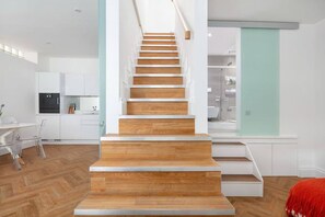 A modern interior with a wooden staircase leading to a second floor. - Charming Mews House in Kensington (London)