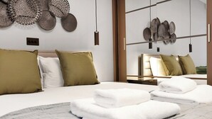 Een moderne hotelkamer met een net opgemaakt bed, decoratieve wandkunst en uitzicht door een glazen scheiding.