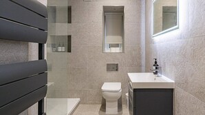 A modern bathroom with a toilet, sink, and a glass shower enclosure. - Spacious Flat in Trendy Brixton (London)