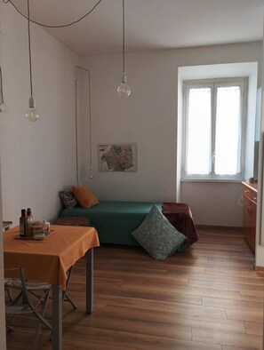 A room with a bed, a table with a tray of bottles, a map on the wall, and a window. - Charming 2-guest Apt in San Giovanni Landmark (Rome)