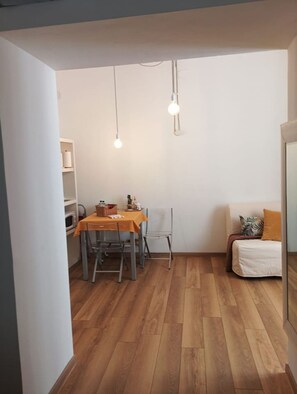 A compact living space with a dining area, a sofa, and a microwave. - Charming 2-guest Apt in San Giovanni Landmark (Rome)
