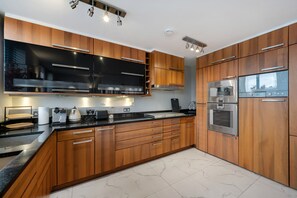 Eine moderne Küche mit Holzschränken, Edelstahlgeräten und einem Marmorboden.
