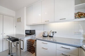 Eine moderne Küche mit weißen Schränken, einer Granit Arbeitsplatte, einem Weinregal und einem Toaster.