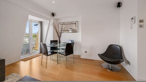 A modern dining area with a glass table, black chairs, and a decorative vase. - Spacious Kensington Apartment With City Views (London)
