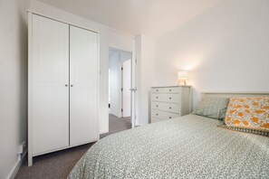 Quarto com cama, guarda-roupa, cômoda e abajur.
