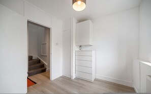 Ein Flur mit Treppe, einer weißen Tür und einer eingebauten weißen Schrankwand.