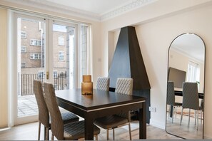 A dining area with a table, chairs, a mirror, and a view through a glass door. - Prime Central London 3-bed Penthouse w Patio (London)