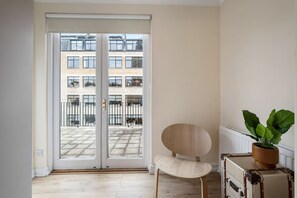 Ein Zimmer mit einer Schiebetür zum Außenbereich, einem Holzstuhl, einem Koffer und einem Topfpflanze.